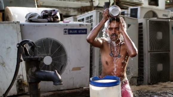 Un jornalero emigrante se baña en un lugar público con un pozo de bombeo en Nueva Delhi (India), en mayo de 2016. Créditos: AP/Altaf Qadri